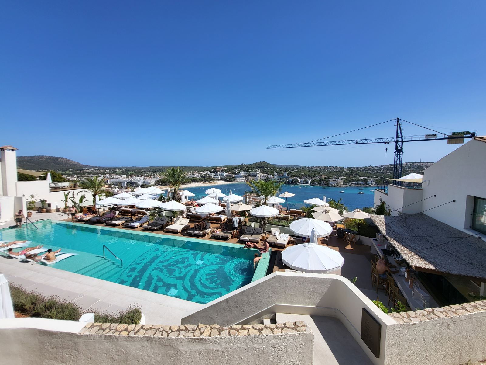 Blick über einen Pool auf eine Bucht am Meer